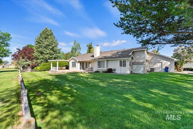 back of property with a lawn, a chimney, and a patio area