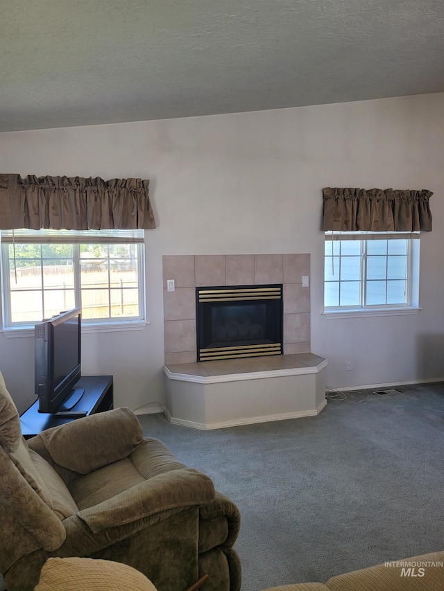 living room featuring carpet, a textured ceiling, and a fireplace