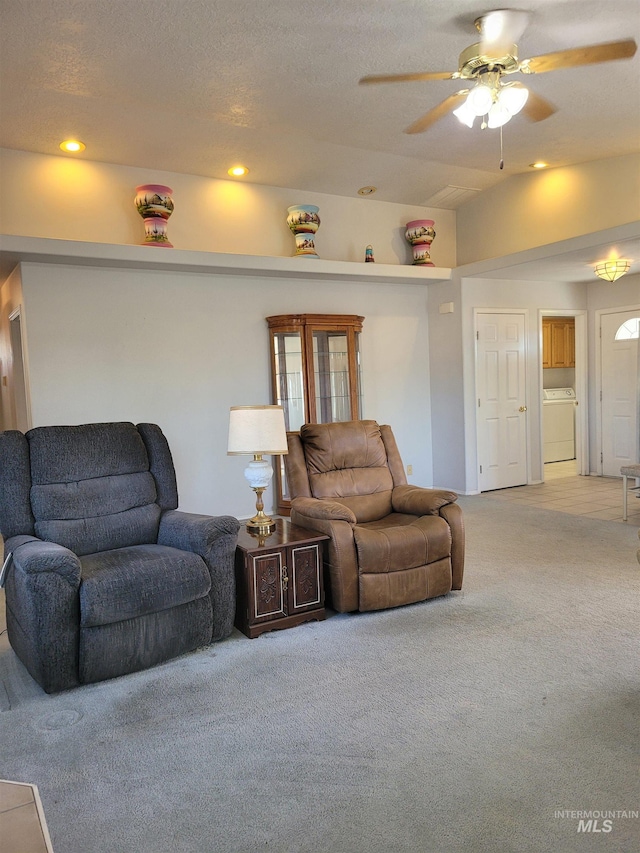 living room with light carpet, washer / clothes dryer, a textured ceiling, and ceiling fan