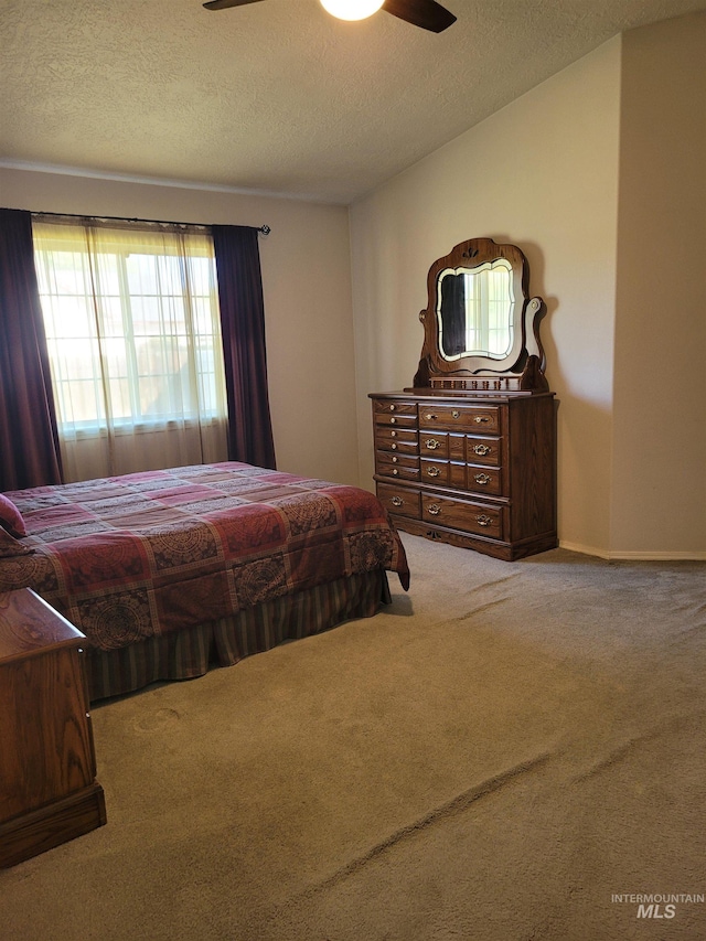 carpeted bedroom with ceiling fan and a textured ceiling