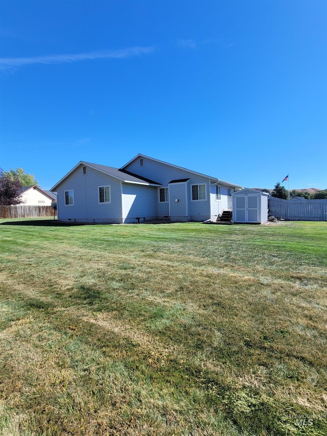 rear view of house featuring a shed and a yard