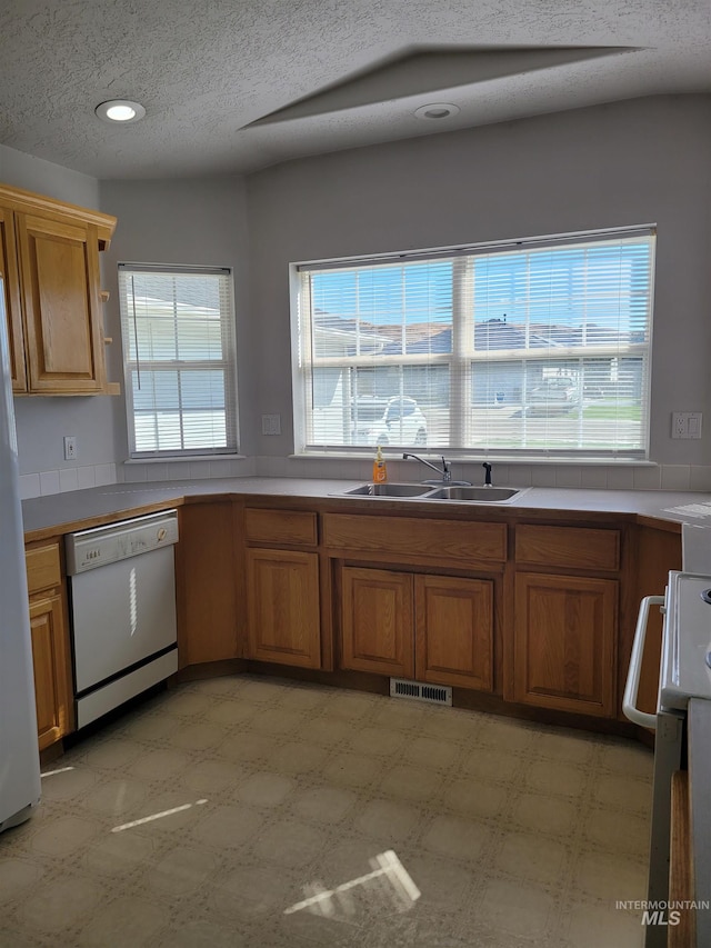 kitchen with white appliances, a textured ceiling, and sink