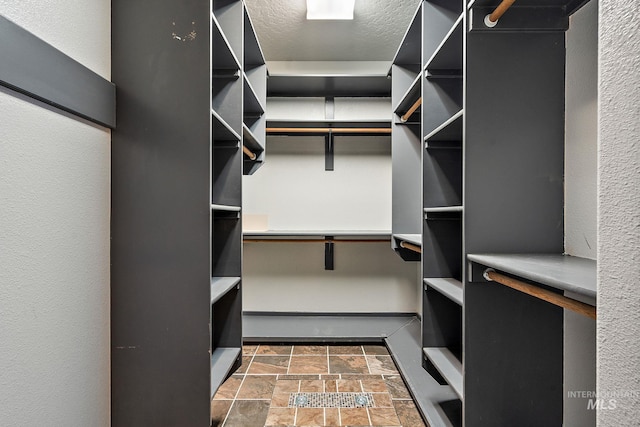 walk in closet featuring stone finish floor