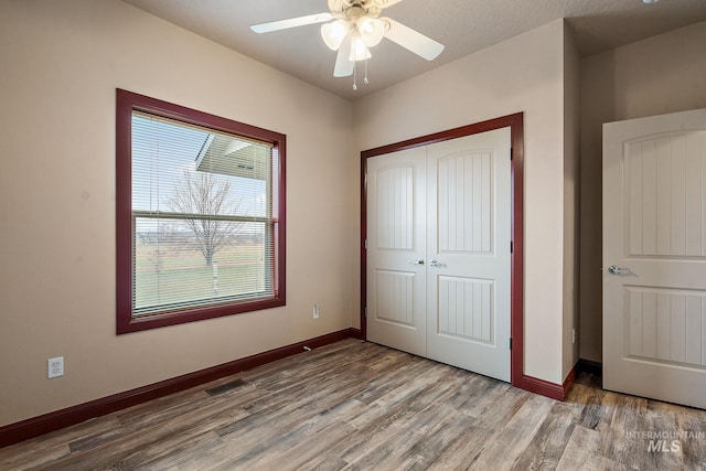 unfurnished bedroom featuring a closet, baseboards, and wood finished floors