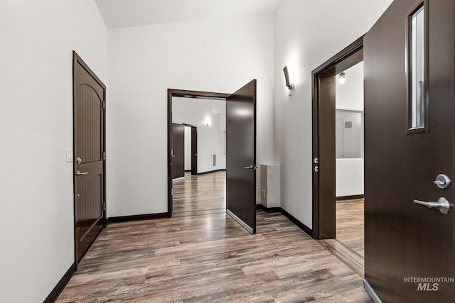 hall with a high ceiling, wood finished floors, and baseboards