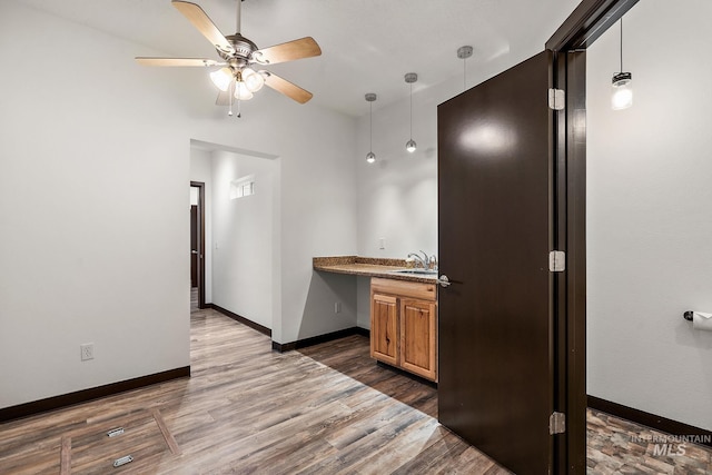 kitchen featuring dark wood-type flooring, baseboards, pendant lighting, brown cabinets, and a ceiling fan