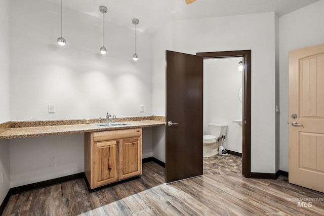 kitchen featuring hanging light fixtures, wood finished floors, baseboards, and a sink