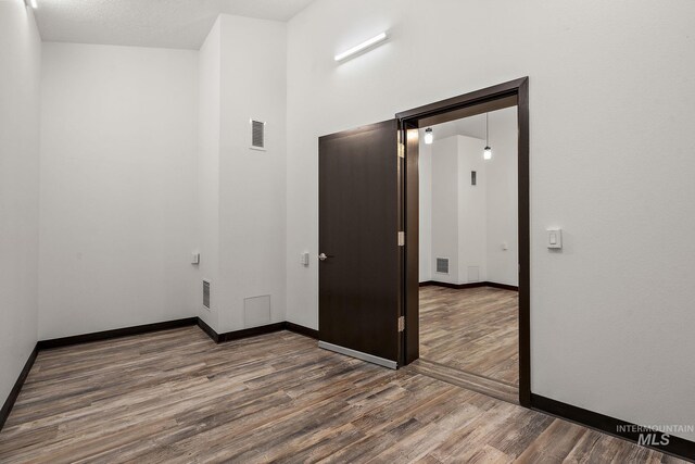 unfurnished room featuring visible vents, wood finished floors, and baseboards