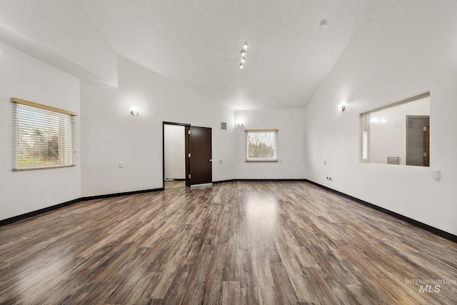 unfurnished room featuring visible vents, wood finished floors, baseboards, and high vaulted ceiling