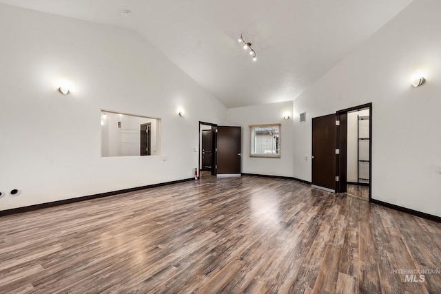 empty room with visible vents, baseboards, high vaulted ceiling, and wood finished floors