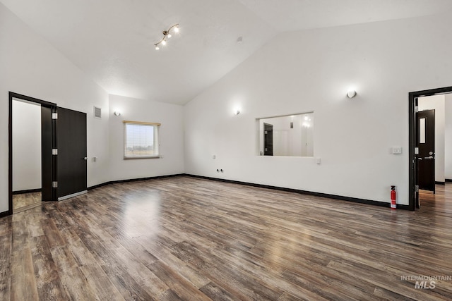 spare room featuring visible vents, high vaulted ceiling, baseboards, and wood finished floors