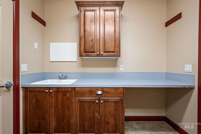 kitchen featuring built in study area, light countertops, baseboards, and a sink