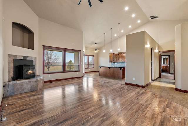 living area with visible vents, high vaulted ceiling, wood finished floors, and a ceiling fan