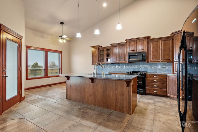 kitchen featuring black appliances, a center island with sink, a sink, a kitchen breakfast bar, and light tile patterned flooring