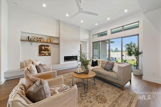 living room with hardwood / wood-style flooring, ceiling fan, and a tile fireplace