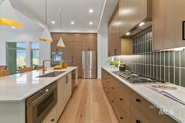 kitchen featuring sink, light hardwood / wood-style flooring, a spacious island, pendant lighting, and appliances with stainless steel finishes