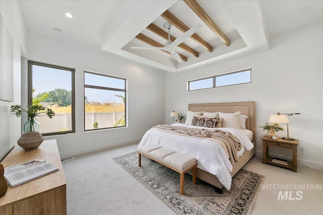 bedroom featuring a raised ceiling, ceiling fan, and light colored carpet