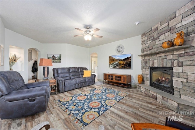 living room featuring a fireplace, a textured ceiling, ceiling fan, and hardwood / wood-style floors