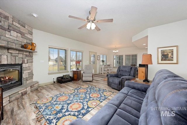 living room with a textured ceiling, light hardwood / wood-style flooring, ceiling fan with notable chandelier, and a fireplace