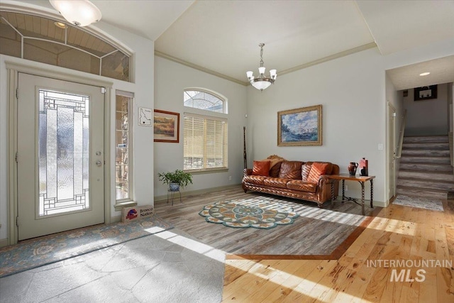 entryway with ornamental molding, light hardwood / wood-style flooring, and an inviting chandelier