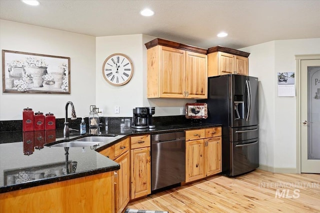 kitchen with dark stone countertops, sink, light hardwood / wood-style flooring, black fridge with ice dispenser, and stainless steel dishwasher