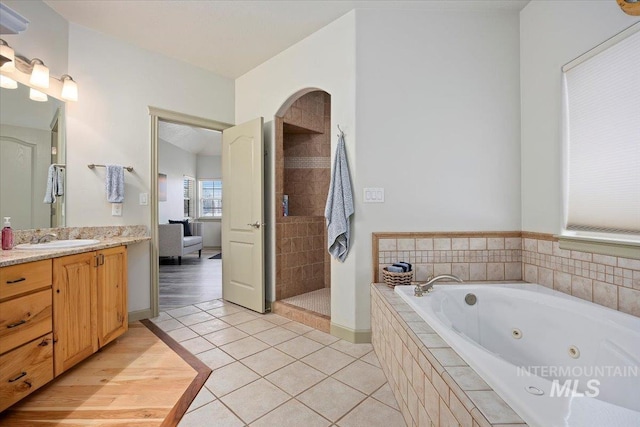 bathroom featuring independent shower and bath, vanity, and tile patterned floors