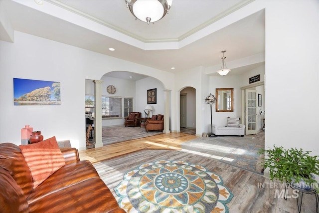 entrance foyer with decorative columns, a raised ceiling, crown molding, and wood-type flooring