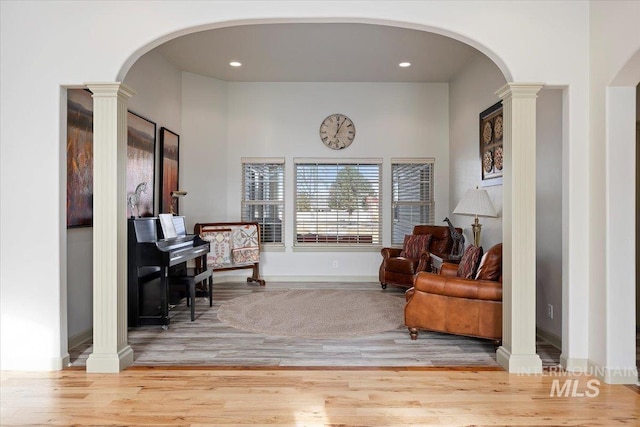 living area with decorative columns and hardwood / wood-style flooring