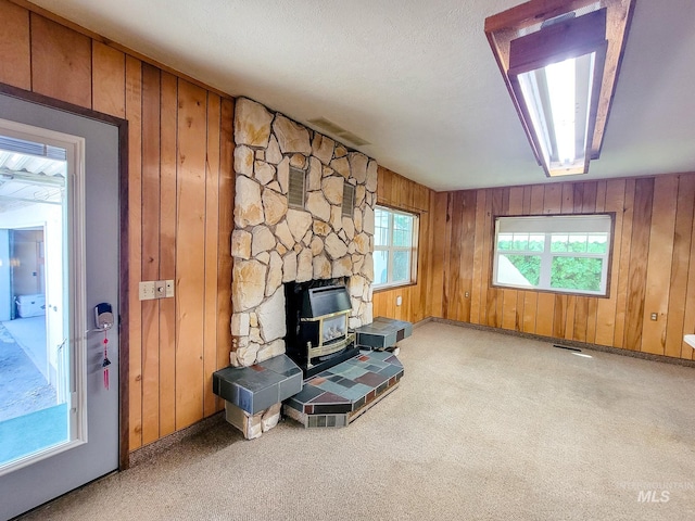 sitting room with a wood stove, wood walls, and carpet floors