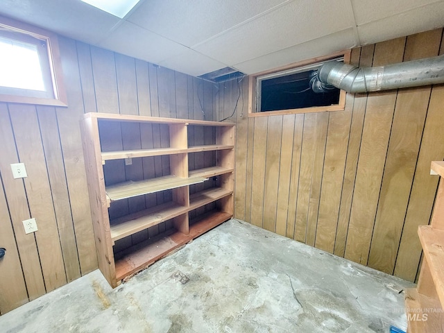 basement with wood walls and a paneled ceiling