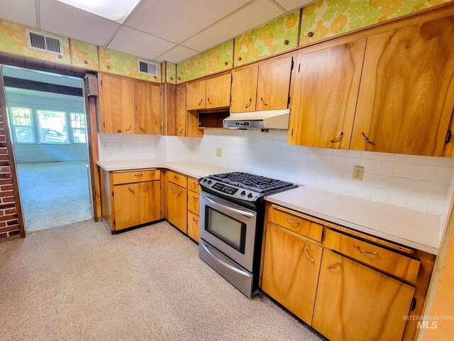 kitchen featuring decorative backsplash, light carpet, stainless steel range with gas stovetop, and a drop ceiling