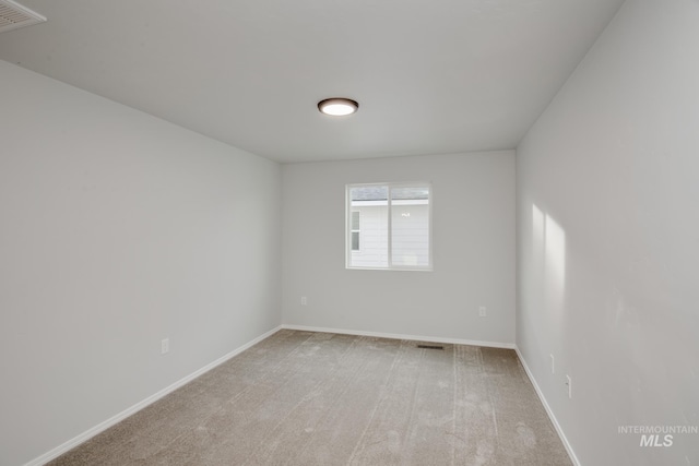 spare room with baseboards, visible vents, and light colored carpet