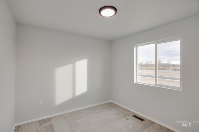 empty room featuring visible vents, light colored carpet, and baseboards