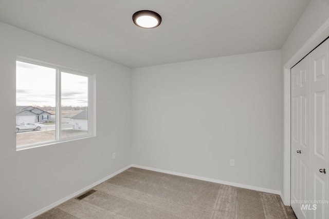unfurnished bedroom with light colored carpet, visible vents, baseboards, and a closet