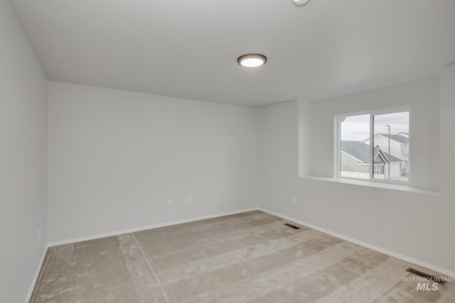 carpeted spare room with visible vents and baseboards