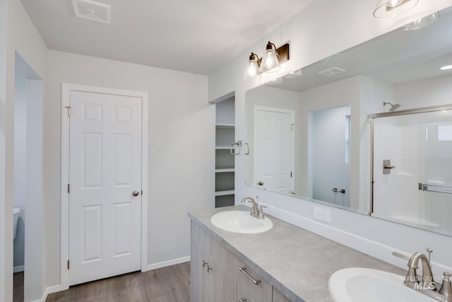 full bath featuring visible vents, a stall shower, wood finished floors, and a sink