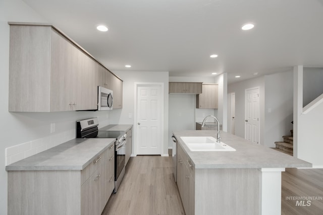 kitchen featuring appliances with stainless steel finishes, light wood-style floors, modern cabinets, and a sink