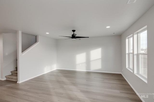 unfurnished living room with recessed lighting, light wood-type flooring, stairs, a ceiling fan, and baseboards