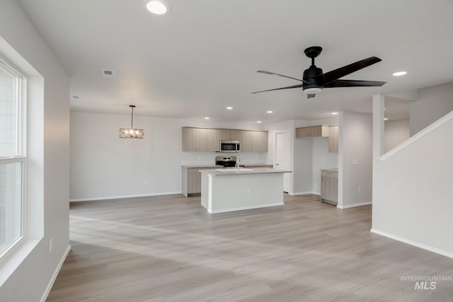 kitchen with stainless steel appliances, light countertops, light wood-style flooring, baseboards, and open floor plan