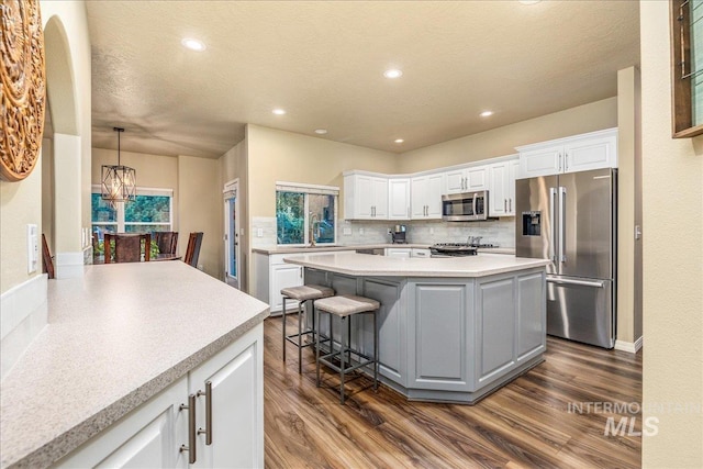 kitchen featuring white cabinetry, a center island, stainless steel appliances, backsplash, and a breakfast bar