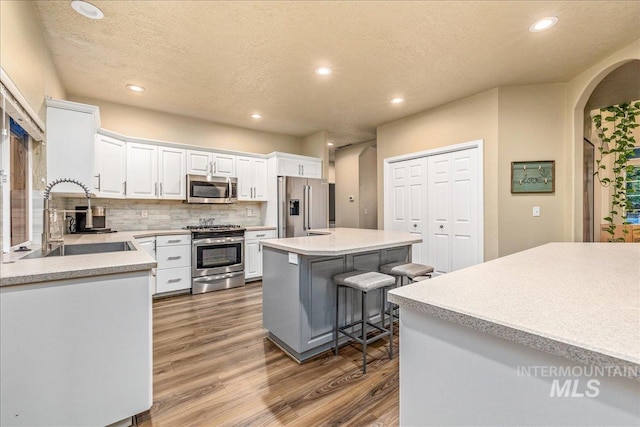 kitchen featuring white cabinetry, sink, a center island, a kitchen breakfast bar, and appliances with stainless steel finishes