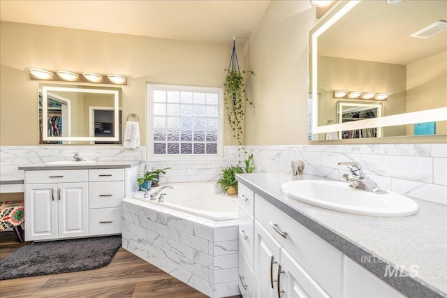 bathroom with vanity, hardwood / wood-style flooring, and tiled tub