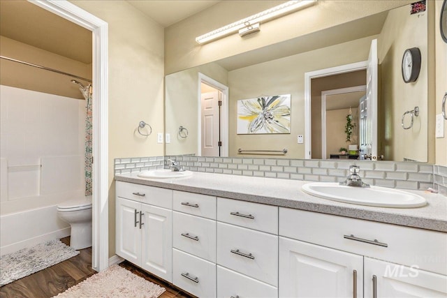 full bathroom with wood-type flooring, toilet, decorative backsplash, shower / washtub combination, and vanity