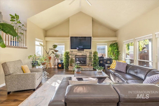 living room featuring a stone fireplace, dark hardwood / wood-style flooring, and high vaulted ceiling