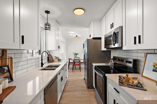 5338 W Spaulding St, Boise, ID 83705 - kitchen with appliances with stainless steel finishes, a sink, light wood-type flooring, tasteful backsplash, and white cabinetry