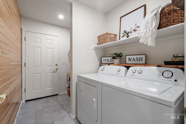 laundry room featuring light tile patterned flooring, washer and clothes dryer, and wood walls