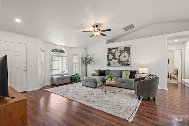 living room with ceiling fan, dark wood-type flooring, vaulted ceiling, and a textured ceiling