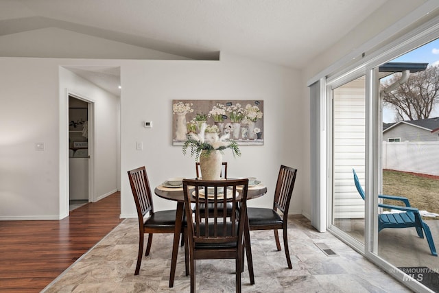 dining space with vaulted ceiling and wood-type flooring