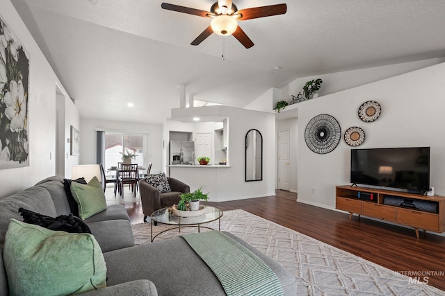 living room with wood-type flooring, lofted ceiling, a textured ceiling, and ceiling fan