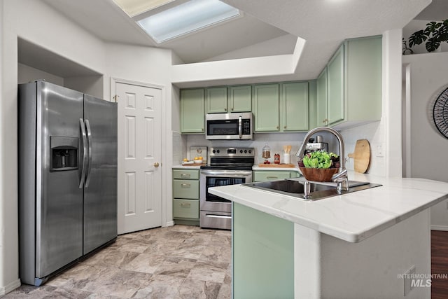 kitchen featuring sink, green cabinets, appliances with stainless steel finishes, tasteful backsplash, and kitchen peninsula